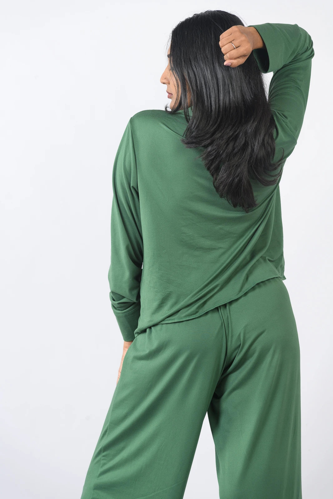Deep green pajama set with a long-sleeve button-up top and wide-leg pants, presented in a relaxed pose against a plain white background.