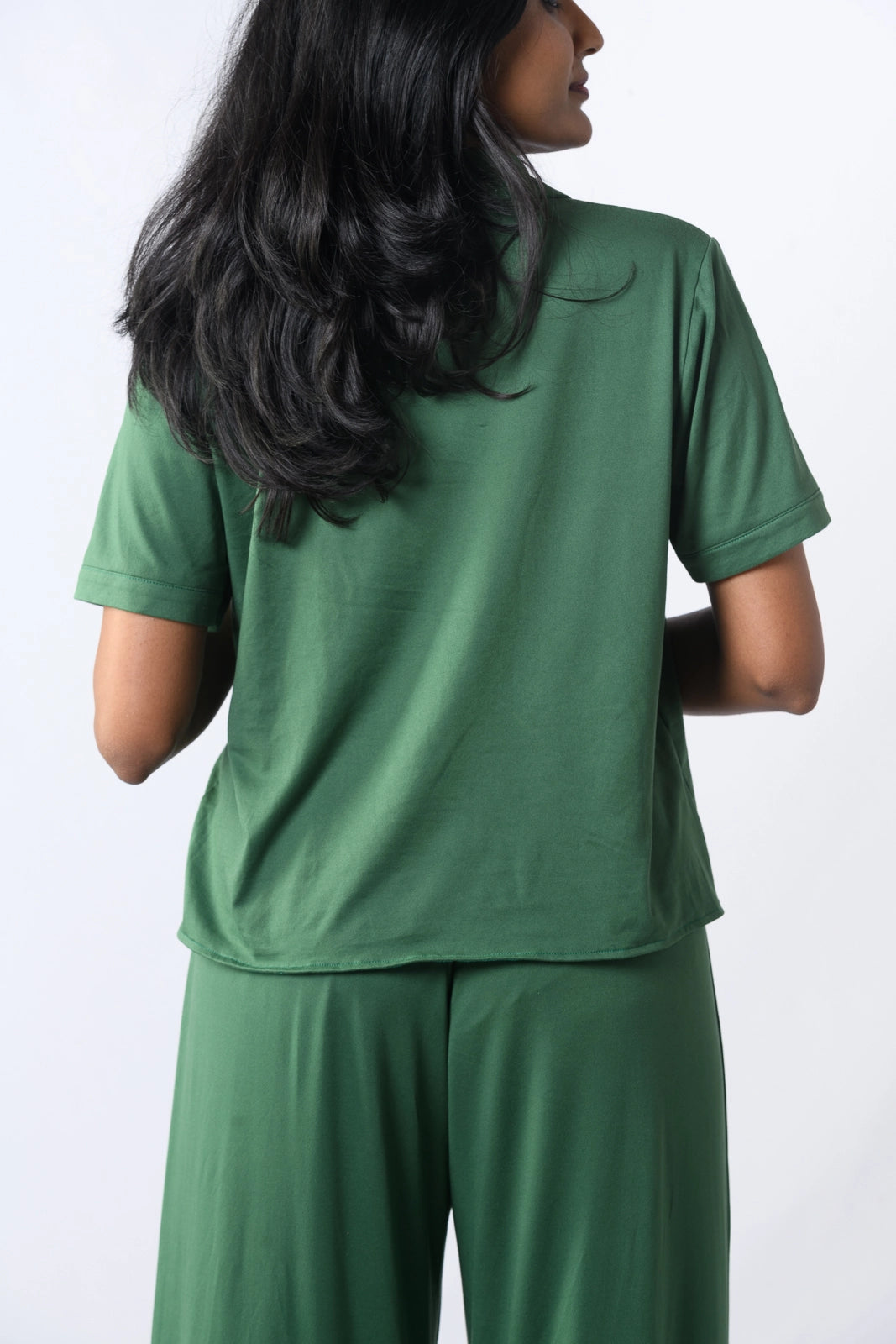 Woman in a green sleeveless pajama set with a flowy top and elastic long pants, perfect for comfortable sleepwear.