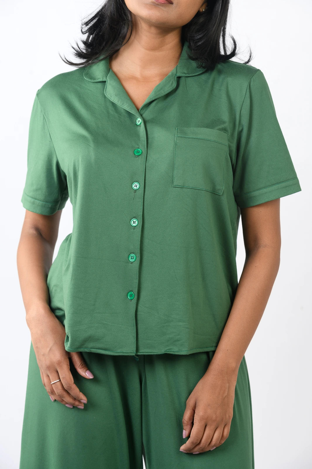 Woman in a green sleeveless pajama set with a flowy top and long pants, perfect for comfortable sleepwear.