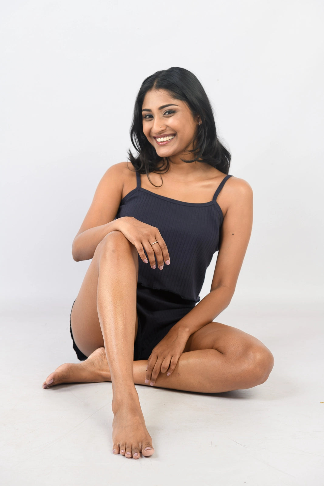 Navy blue ribbed loungewear set with a spaghetti-strap top and matching shorts, styled in a side profile against a plain white background.